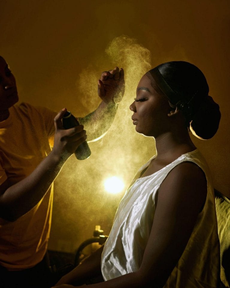 A woman receives Tanning spray on her face from a man, showcasing a professional beauty session in Avondale
